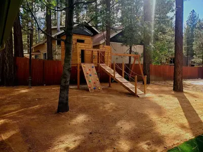 a playground in front of a house with a tree at Big Bear Splash Home in Big Bear Lake