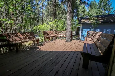 two benches sitting on a wooden deck with trees at Mountain Air Home in Big Bear Lake
