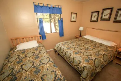 a bedroom with two beds and a window with blue curtains at Family Fun House in Big Bear Lake
