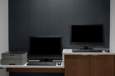 two computer monitors and a printer on a desk at Courtyard Los Angeles Burbank Airport in Burbank