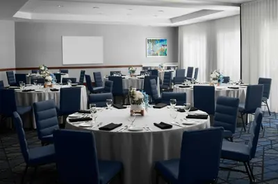 a conference room with round tables and blue chairs at Courtyard Los Angeles Burbank Airport in Burbank