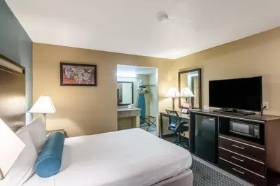 a hotel room with a bed and a flat screen tv at Glenridge Inn Glendale - Pasadena in Glendale