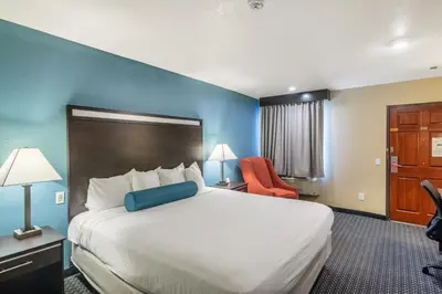 a hotel room with a large bed with a blue wall at Glenridge Inn Glendale - Pasadena in Glendale