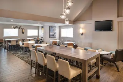 a dining room with tables and chairs and a flat screen tv at Residence Inn by Marriott Long Beach in Long Beach