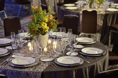 a table with plates and glasses and a vase of flowers at Hotel MDR Marina del Rey- a DoubleTree by Hilton in Los Angeles