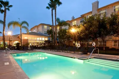 a pool with chairs and palm trees in a hotel at Residence Inn Los Angeles LAX/El Segundo in El Segundo