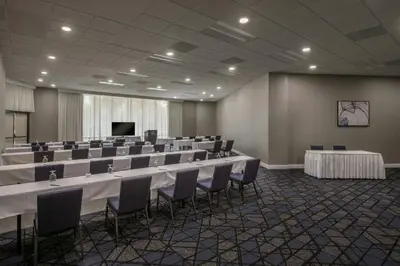 a conference room with tables and chairs and a screen at Courtyard by Marriott Los Angeles Pasadena/Monrovia in Monrovia