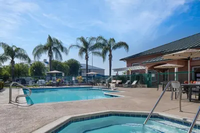 a pool with a table and chairs and palm trees at Residence Inn by Marriott Santa Clarita Valencia in Santa Clarita