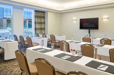 a conference room with tables and chairs and a screen at Warner Center Marriott Woodland Hills in Woodland Hills