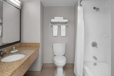 a bathroom with a toilet and a sink and a tub at Courtyard by Marriott Cypress Anaheim / Orange County in Cypress