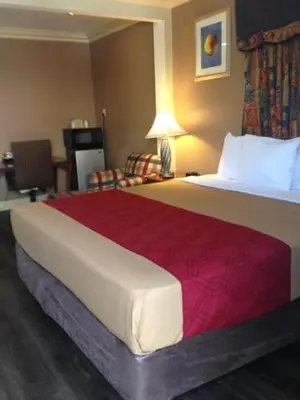 a hotel room with a large bed and a chair at Pacifica Motel in Long Beach