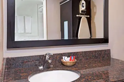 a bathroom sink with a mirror and a basket of toothbrushes at Super 8 by Wyndham Los Angeles-Culver City Area in Los Angeles