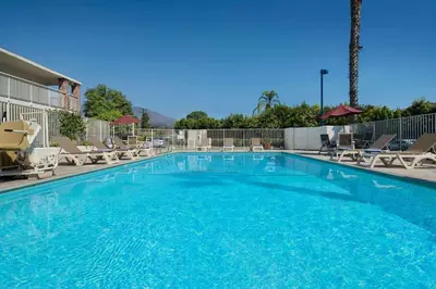 a large swimming pool with chairs and a volley ball court at Motel 6-Arcadia, CA - Los Angeles - Pasadena Area in Arcadia