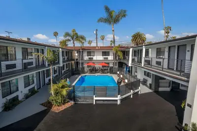 an apartment building with a swimming pool and palm trees at Sunset West Hotel, SureStay Collection By Best Western in Los Angeles
