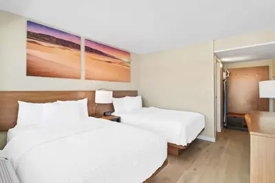 two beds in a hotel room with white sheets at Clarion Pointe Ridgecrest near China Lake Naval Station in Ridgecrest