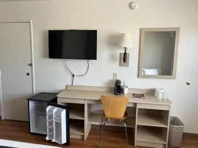 a room with a desk with a television on the wall at Motel 6-Stanton, CA- Anaheim West in Stanton