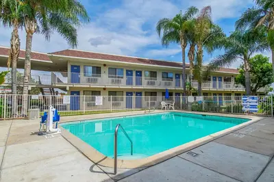 a swimming pool in front of a building with palm trees at Motel 6-Bakersfield, CA - Airport in Bakersfield
