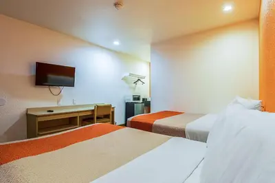 a hotel room with two beds and a desk at Motel 6-Bakersfield, CA - Airport in Bakersfield