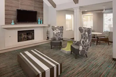 a living room with a fireplace and chairs and a tv at Residence Inn by Marriott Ontario Airport in Ontario