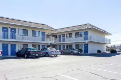 a large apartment building with cars parked in a parking lot at Motel 6-Mojave, CA in Mojave