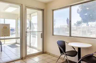 a waiting room with a table and chairs and windows at Motel 6-Mojave, CA in Mojave