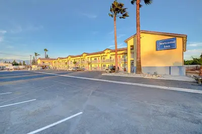 an empty parking lot in front of a yellow building at Welcome Inn San Bernardino/ Colton in Colton