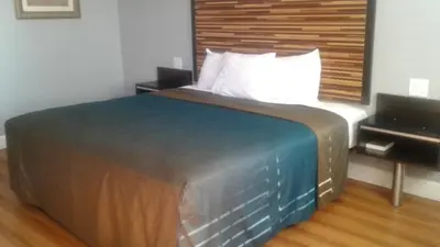 a bedroom with a large bed with a wooden headboard at Welcome Inn San Bernardino/ Colton in Colton