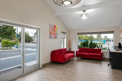a lobby with two red chairs and sliding glass doors at Solara Inn and Suites in Anaheim