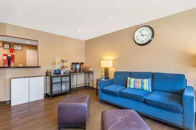 a living room with a blue couch and a clock on the wall at Comfort Inn Monterey Park - Los Angeles in Monterey Park