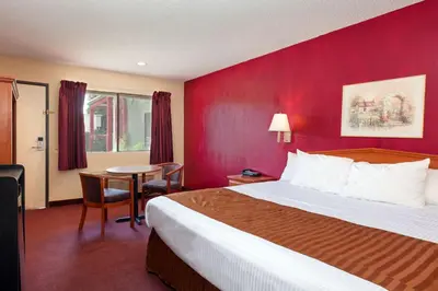 a hotel room with a bed and a red wall at America's Best Value Inn & Suites Bakersfield Central in Bakersfield