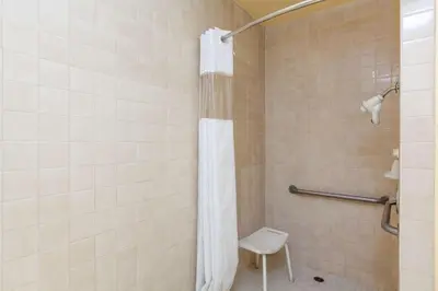 a bathroom with a shower with a toilet and a stool at America's Best Value Inn & Suites Bakersfield Central in Bakersfield