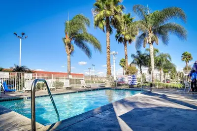 a swimming pool with palm trees in a resort at Motel 6-Riverside, CA - South in Riverside
