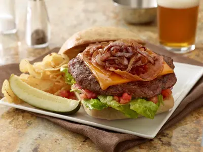 a cheeseburger on a plate with chips and a drink at Hyatt Place Delano in Delano
