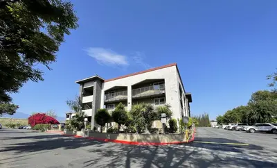 a building with trees in front of a parking lot at Quality Inn Ontario Airport Convention Center in Ontario