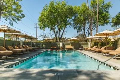 a swimming pool with chairs and umbrellas at Hummingbird Inn in Ojai