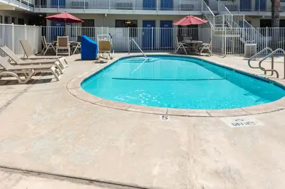 a swimming pool at a resort with chairs and umbrellas at Motel 6 Bakersfield, CA - Convention Center in Bakersfield