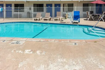 a swimming pool with chairs and an umbrella at Motel 6 Bakersfield, CA - Convention Center in Bakersfield