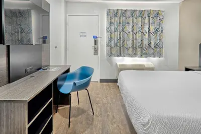 a small room with a bed and a blue chair at Motel 6-Lancaster, CA in Lancaster