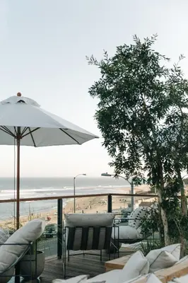 a patio with chairs and an umbrella and a beach at The Surfrider Malibu in Malibu