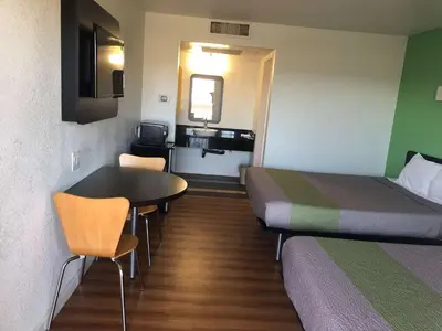a small room with two beds and a table and chairs at Motel 6-Barstow, CA in Barstow