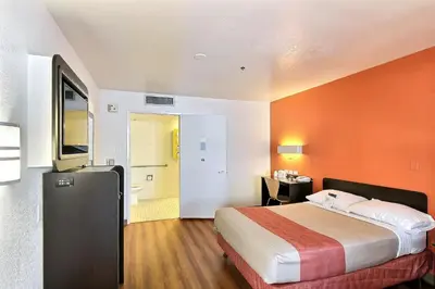 a bedroom with a large bed and an orange wall at Motel 6-Thousand Oaks, CA in Thousand Oaks