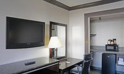 a hotel room with a desk and a flat screen tv at Hawthorne Plaza Inn Near LAX in Hawthorne
