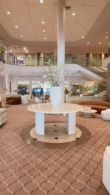 a lobby with a large vase with flowers on a table at Oxford Palace Hotel in Los Angeles