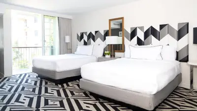 a bedroom with two beds and a large window at Chamberlain West Hollywood in Los Angeles