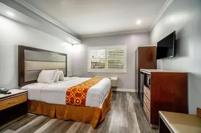 a hotel room with a bed and a flat screen tv at Rodeway Inn & Suites Pasadena in Pasadena