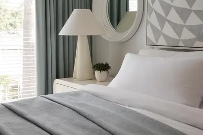 a bedroom with a bed with a lamp and a mirror at Avalon Hotel Beverly Hills, a Member of Design Hotels in Los Angeles