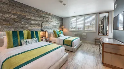 a bedroom with two beds and a brick wall at Lexen Hotel - North Hollywood Near Universal Studios in North Hollywood