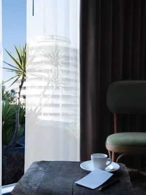 a table with a cup of coffee on it next to a window at The Aster in Los Angeles