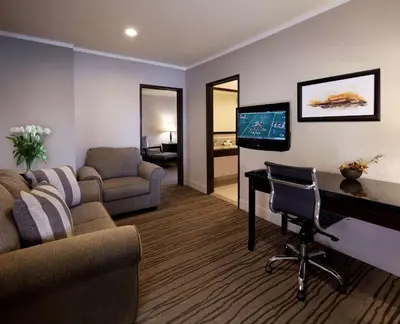 a living room with a couch and a desk and a tv at DoubleTree by Hilton Claremont in Claremont