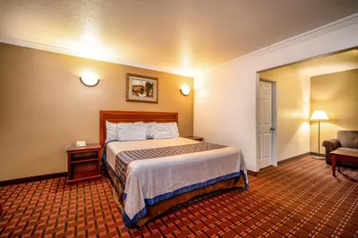 a hotel room with a bed and a chair at Regency Inn & Suites Downey in Downey